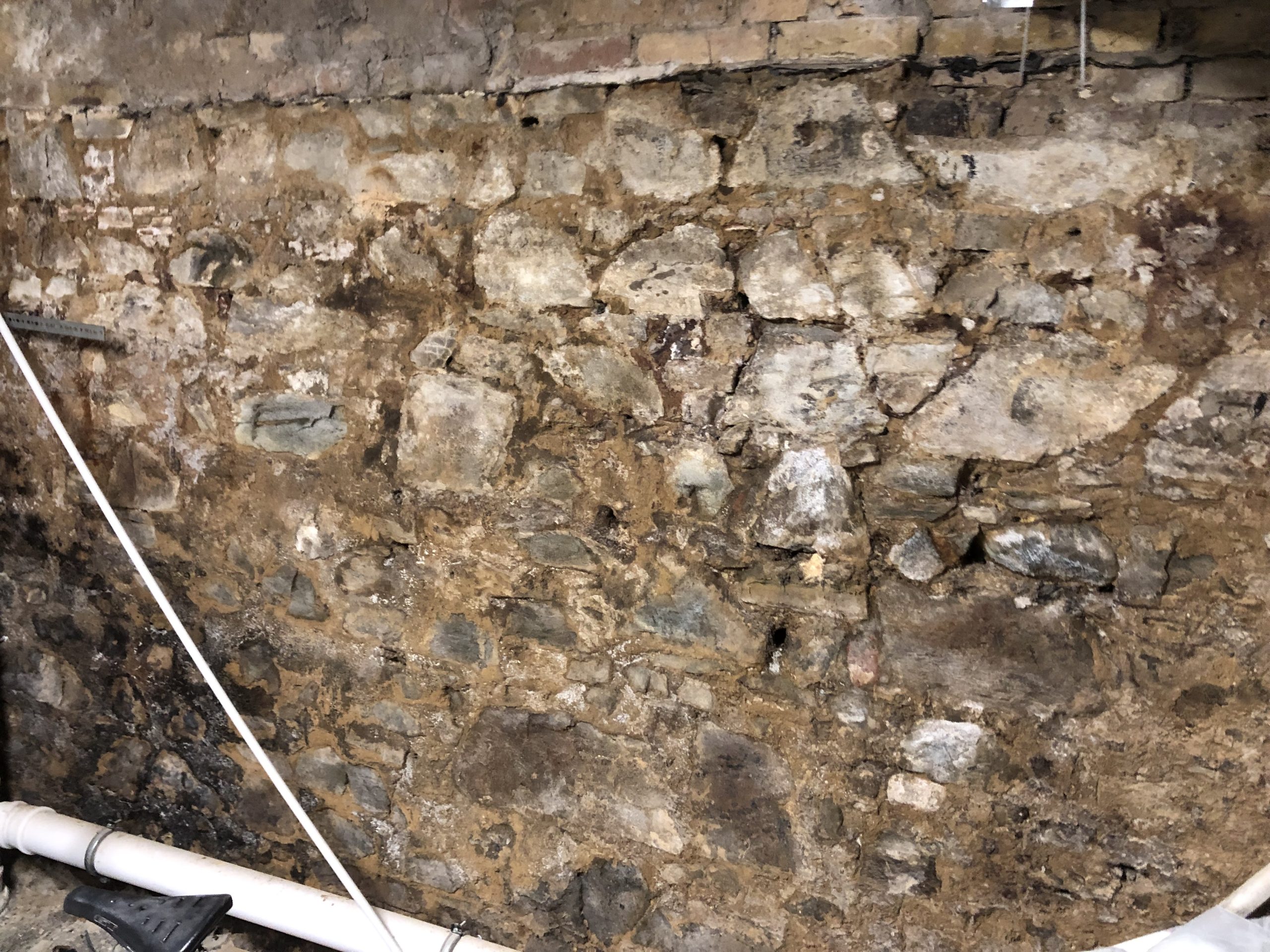 Stark durchfeuchtete Kellerwand aus Bruchstein mit typischen Schäden durch aufsteigende und seitlich eindringende Feuchtigkeit